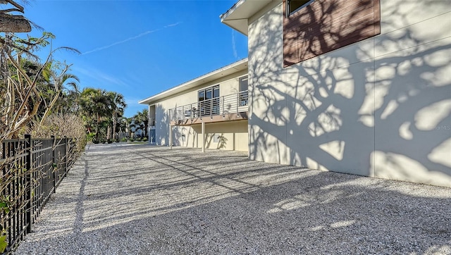 view of side of property with fence and a balcony