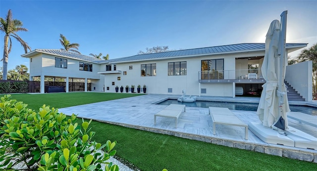 rear view of house featuring metal roof, stairs, a yard, stucco siding, and a patio area