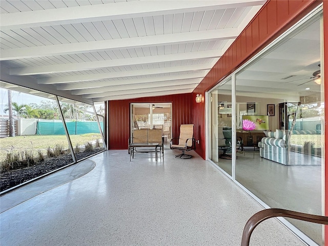 unfurnished sunroom featuring ceiling fan and vaulted ceiling with beams