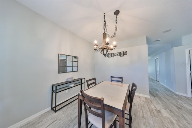 dining room with light hardwood / wood-style flooring and an inviting chandelier