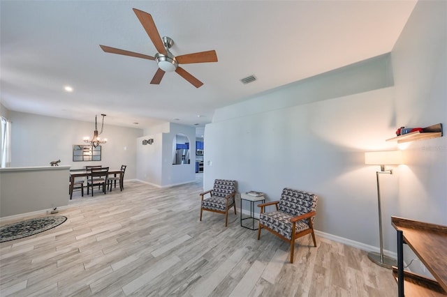 sitting room featuring ceiling fan with notable chandelier and light hardwood / wood-style floors