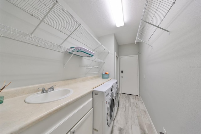 washroom with sink, washing machine and dryer, and light hardwood / wood-style floors