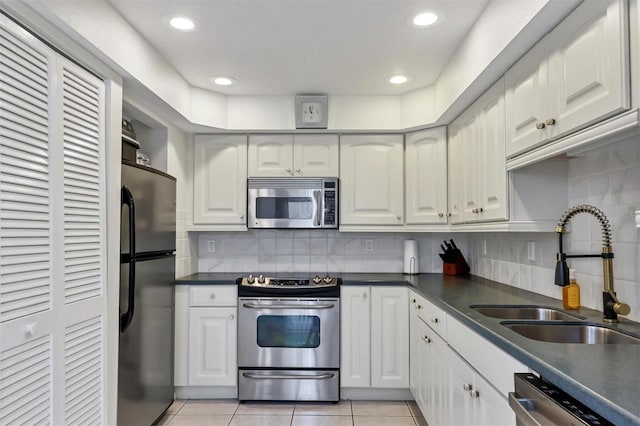 kitchen with stainless steel appliances, decorative backsplash, white cabinetry, and sink