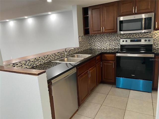 kitchen featuring appliances with stainless steel finishes, sink, kitchen peninsula, backsplash, and light tile patterned flooring