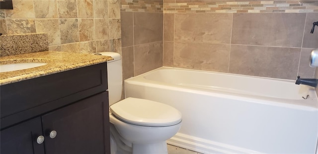 bathroom featuring tile walls, toilet, vanity, and a tub to relax in