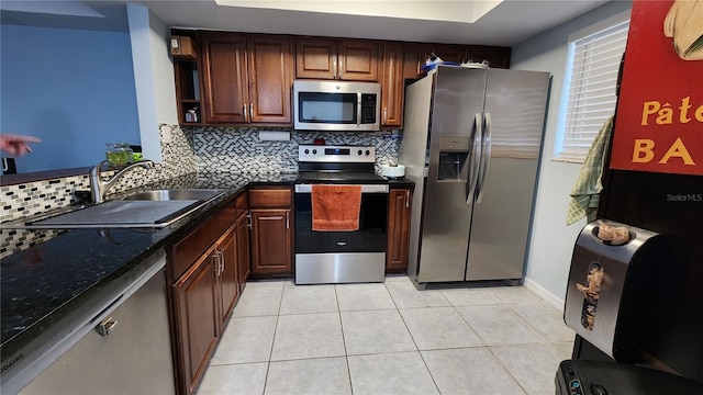 kitchen featuring a raised ceiling, sink, backsplash, light tile patterned floors, and stainless steel appliances