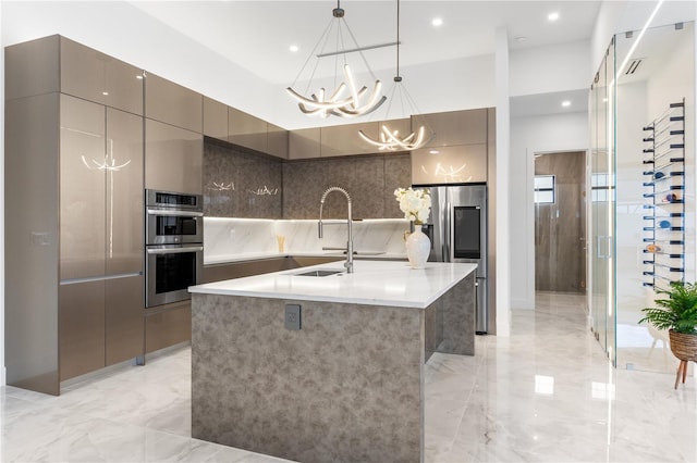 kitchen with a notable chandelier, hanging light fixtures, sink, an island with sink, and stainless steel appliances