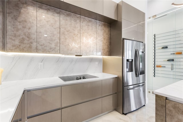 kitchen featuring gray cabinets, black electric stovetop, stainless steel fridge, and light stone counters