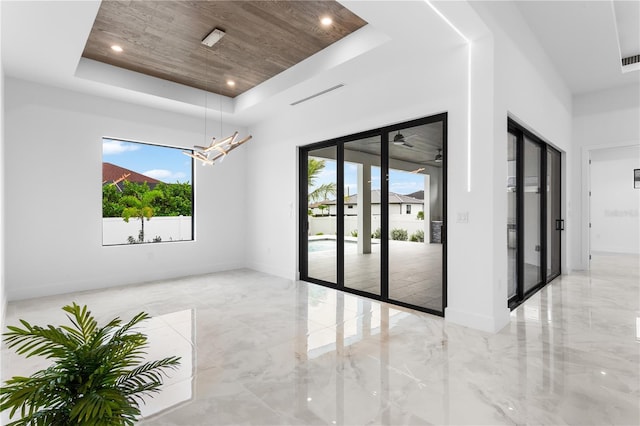 unfurnished room featuring wood ceiling and a raised ceiling