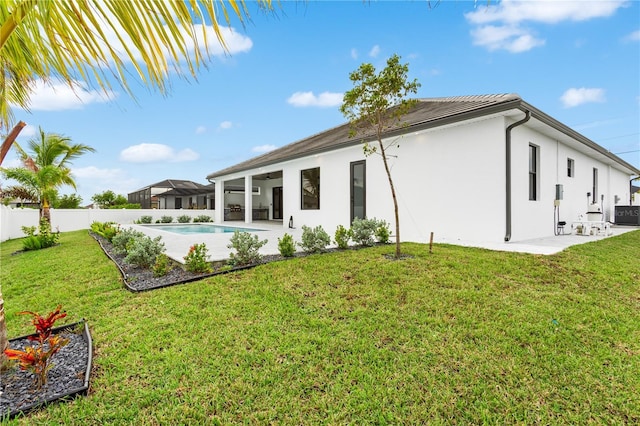 back of property with a patio area, a fenced in pool, and a lawn