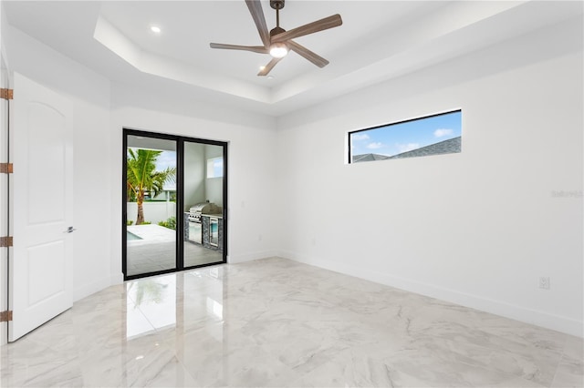 unfurnished room with ceiling fan and a tray ceiling