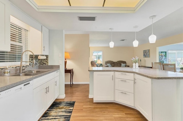 kitchen featuring a sink, visible vents, decorative backsplash, dishwasher, and light wood finished floors