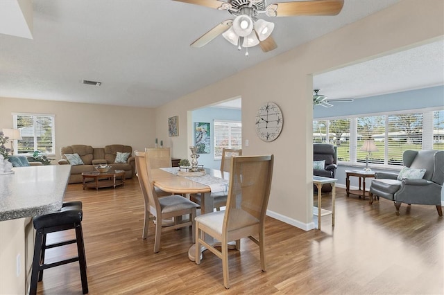 dining room with light wood-style flooring, visible vents, and baseboards