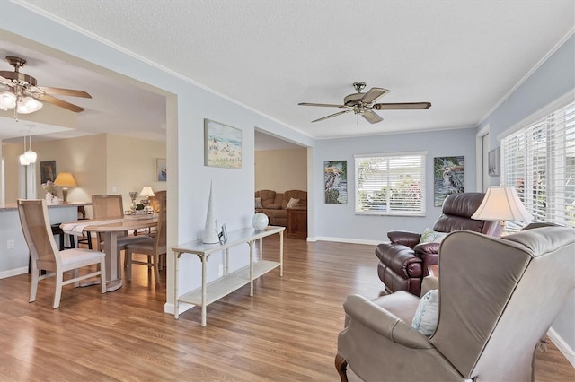 sitting room with light wood-style floors, ceiling fan, and ornamental molding