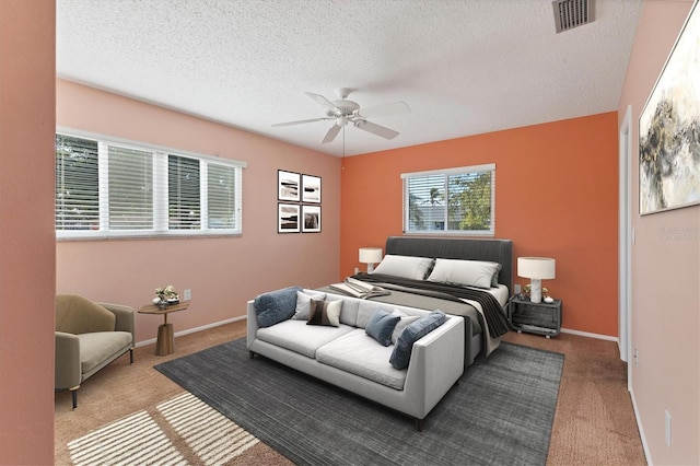 carpeted bedroom featuring baseboards, visible vents, ceiling fan, and a textured ceiling