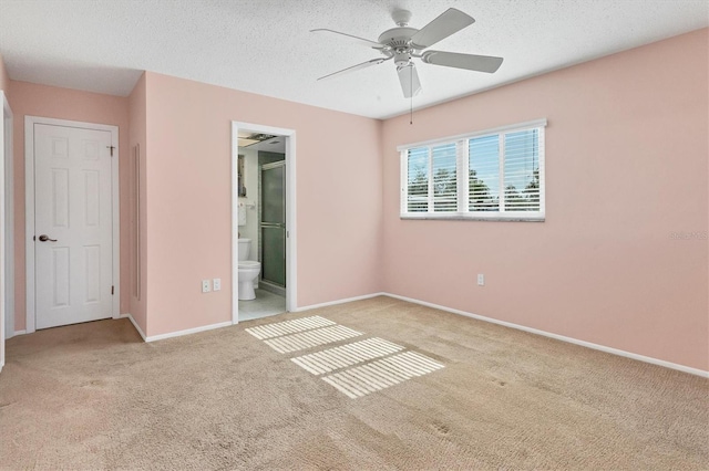 unfurnished bedroom with carpet, ensuite bath, a textured ceiling, and baseboards