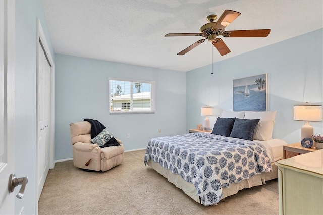 carpeted bedroom with a textured ceiling, a closet, a ceiling fan, and baseboards