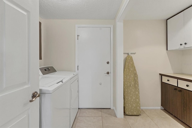 laundry room featuring washing machine and clothes dryer, light tile patterned floors, cabinet space, a textured ceiling, and baseboards