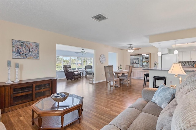 living room featuring baseboards, visible vents, and wood finished floors