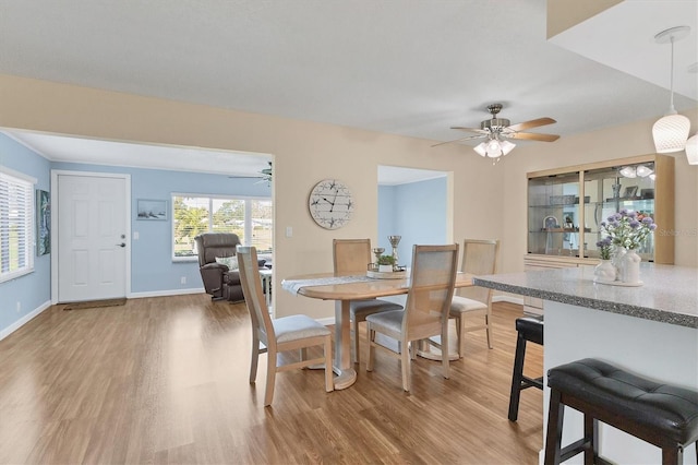 dining room featuring a ceiling fan, light wood-type flooring, and baseboards