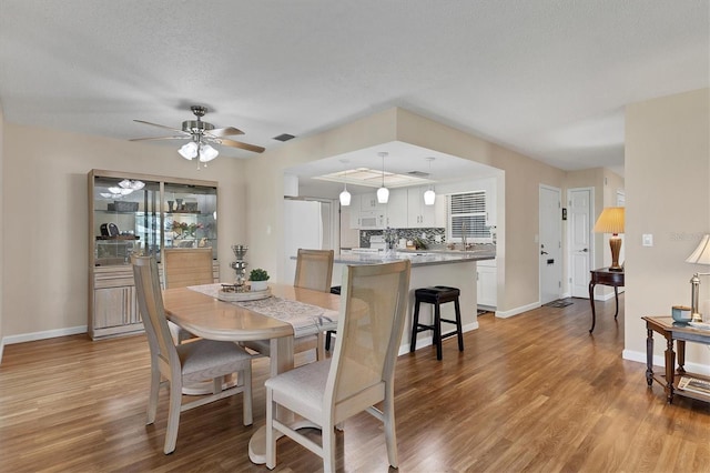 dining room featuring light wood-style flooring, baseboards, and a ceiling fan