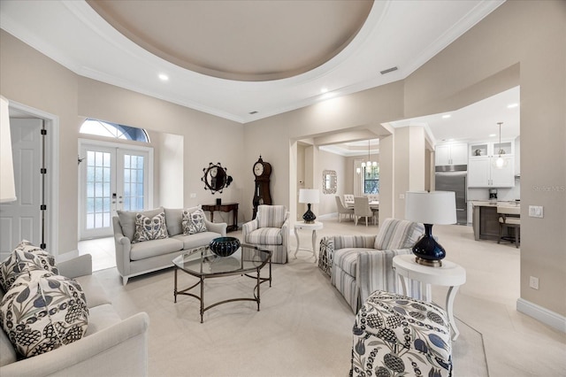 living room featuring light tile patterned floors, a tray ceiling, ornamental molding, and french doors