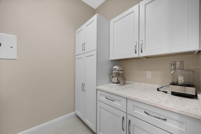 kitchen featuring light stone counters, white cabinetry, and light tile patterned floors