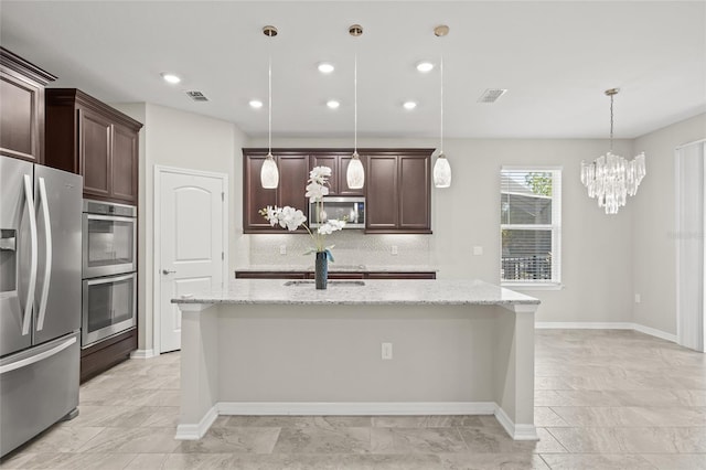 kitchen with stainless steel appliances, decorative light fixtures, decorative backsplash, and a kitchen island with sink