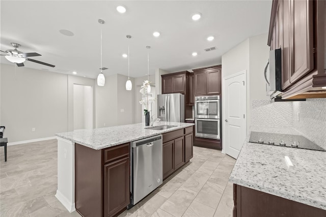 kitchen with decorative light fixtures, decorative backsplash, a kitchen island with sink, and appliances with stainless steel finishes