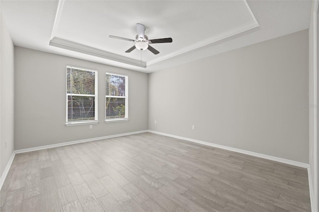 spare room with ceiling fan, baseboards, wood finished floors, and a tray ceiling