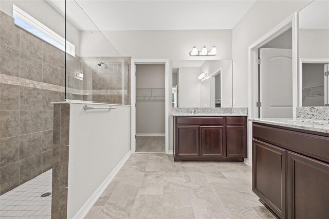 full bathroom with walk in shower, vanity, a spacious closet, and marble finish floor