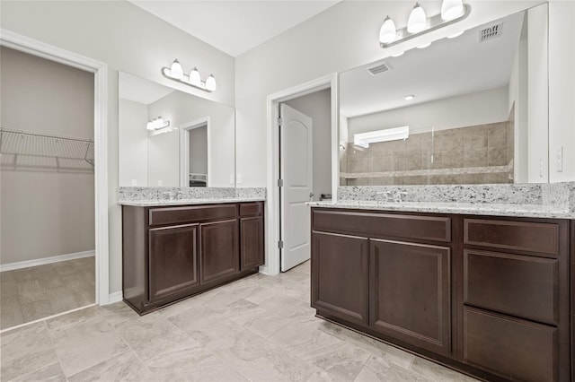 bathroom featuring a walk in closet, visible vents, vanity, and a walk in shower