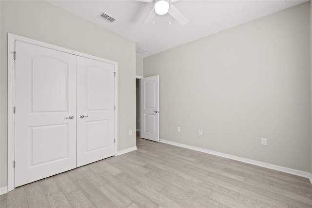 unfurnished bedroom with baseboards, light wood-style floors, visible vents, and a closet