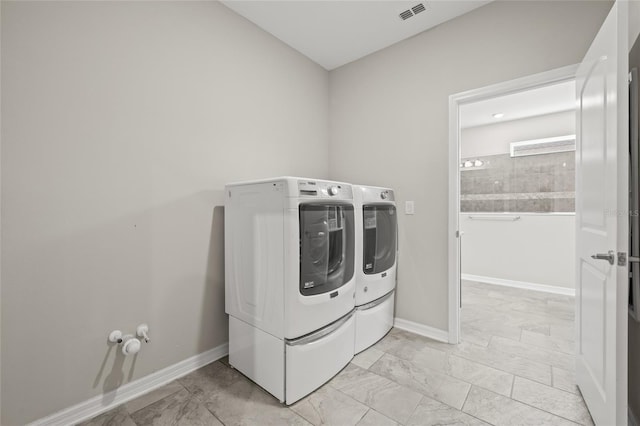clothes washing area with baseboards, visible vents, washer and dryer, and laundry area