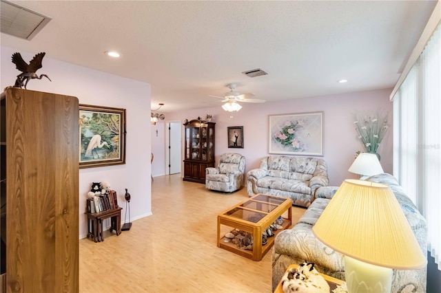 living room featuring ceiling fan, a textured ceiling, and hardwood / wood-style floors