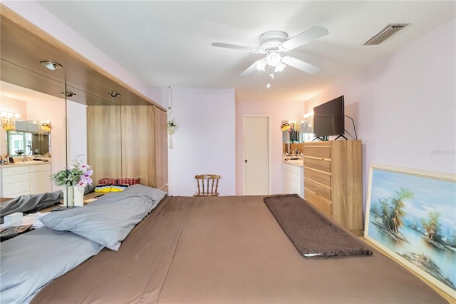 bedroom featuring a textured ceiling, ceiling fan, and ensuite bath