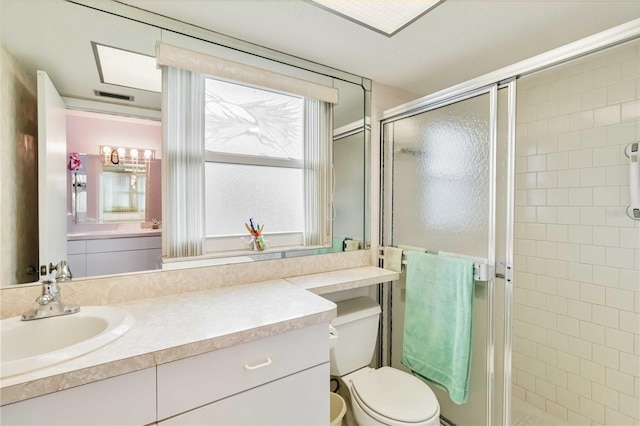 bathroom with a shower with shower door, vanity, and toilet