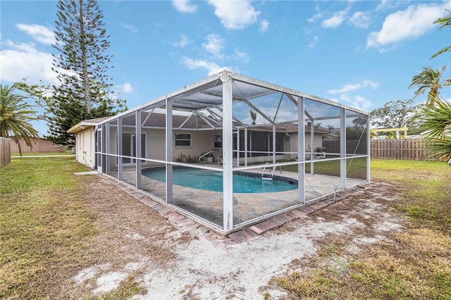 view of pool with glass enclosure, a lawn, and a patio