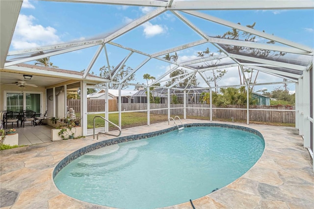 view of swimming pool with ceiling fan, glass enclosure, and a patio area