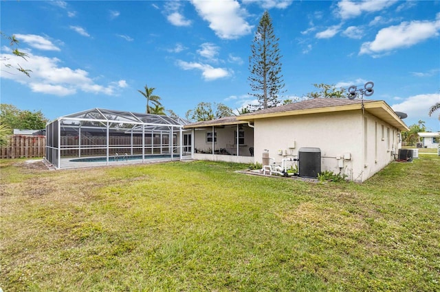 rear view of property featuring a lawn, central air condition unit, and glass enclosure