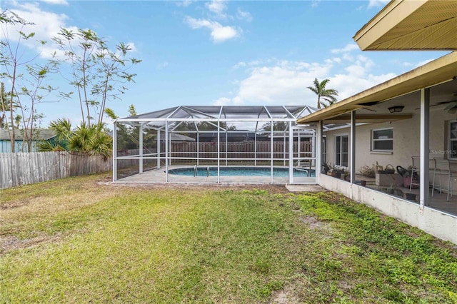 view of yard with glass enclosure, a fenced in pool, and ceiling fan