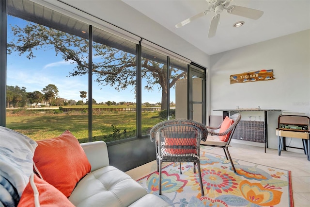 sunroom / solarium featuring ceiling fan and a rural view