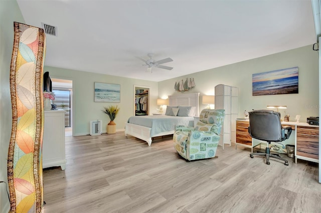 bedroom featuring ceiling fan, a closet, a walk in closet, and light hardwood / wood-style flooring