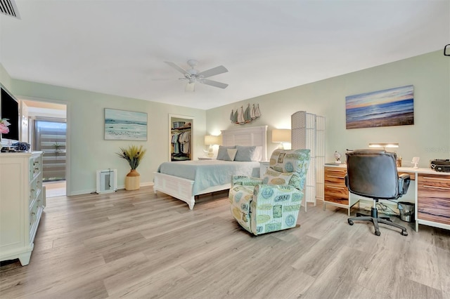 bedroom featuring a spacious closet, ceiling fan, a closet, and light hardwood / wood-style floors