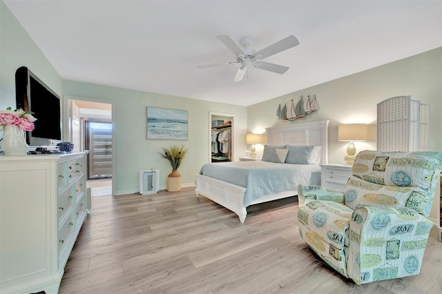 bedroom featuring a spacious closet, a closet, light hardwood / wood-style flooring, and ceiling fan