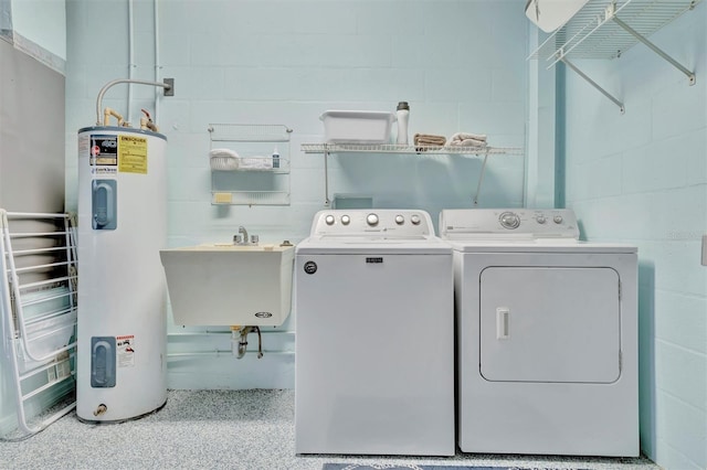 clothes washing area featuring electric water heater, sink, and separate washer and dryer