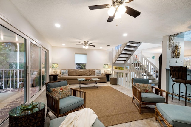 living room featuring a textured ceiling, ceiling fan, and light tile patterned floors