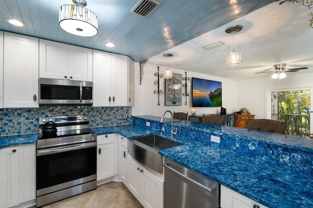 kitchen featuring stainless steel appliances, decorative light fixtures, white cabinetry, and sink