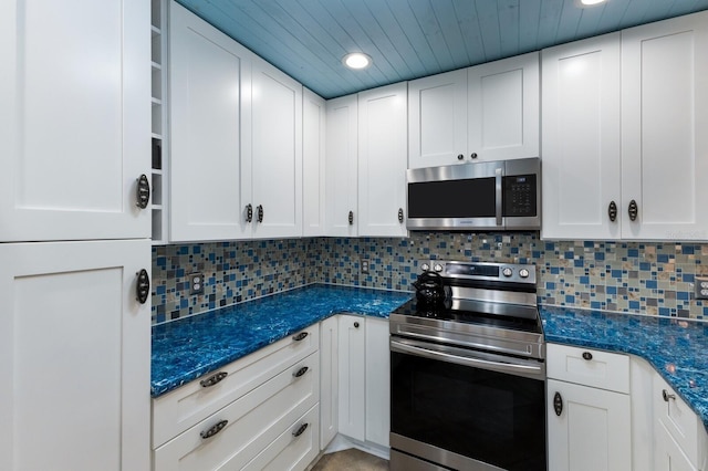 kitchen with dark stone counters, decorative backsplash, white cabinetry, and appliances with stainless steel finishes