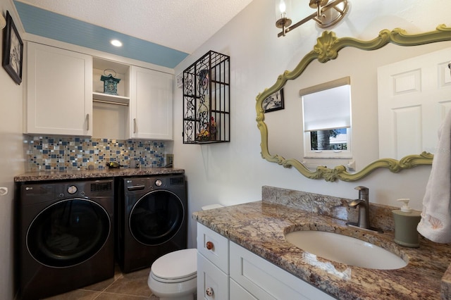 laundry area with sink, tile patterned floors, a textured ceiling, and independent washer and dryer